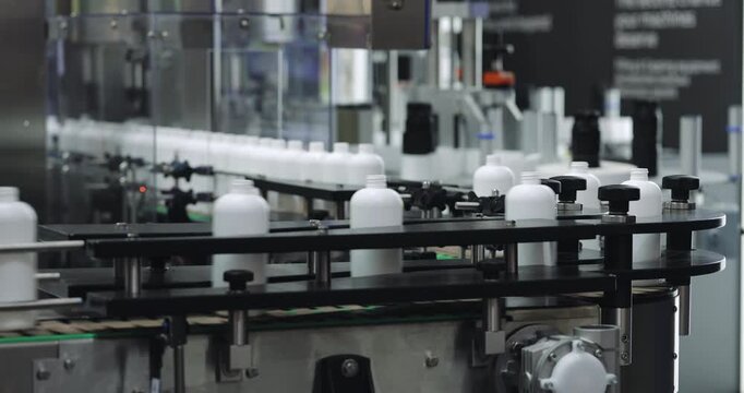 Plastic containers for household chemicals circulate on factory conveyor during packaging. Advanced production equipment supports high-speed manufacturing