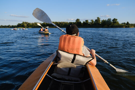 Boy in life jacket kayaking on calm river water during sunny summer day, outdoor active lifestyle and water sport concept