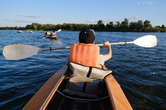 Boy in life jacket kayaking on calm river water during sunny summer day, outdoor active lifestyle and water sport concept