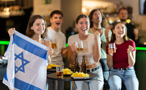 Group of friends cheer together for their favorite Israeli team in a beer bar
