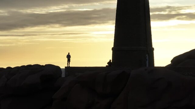 Perros-Guirec, France - 28 June 2026: Aerial view of Phare de Men Ruz with people in silhouette against the sunrise sky.