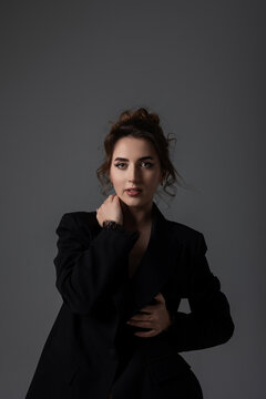 Woman poses in a black blazer with a neutral background in a studio setting