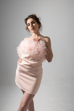Model poses in a pink dress with tulle in studio setting