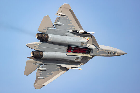 Stealth fighter jet banking with thrust vectoring and open weapons bay