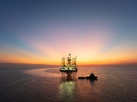 Aerial view from a drone of big jack up offshore drilling oil rig and production platform in the ocean during sunset - Oil and Gas Industry