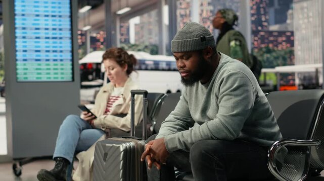 Weary traveler dozes on a bus stop bench during a delayed route, with an African American man napping on a chair after becoming exhausted by slow public transit arriving late during the travel delay.