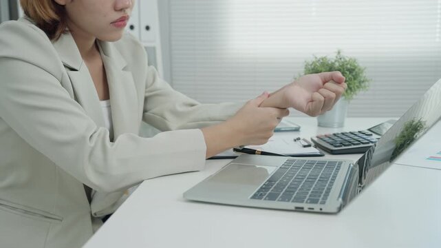 business young woman working in office with a carpal tunnel syndrome or wrist joint inflammation, hand muscle inflammation from office syndrome , hand muscle pain from working