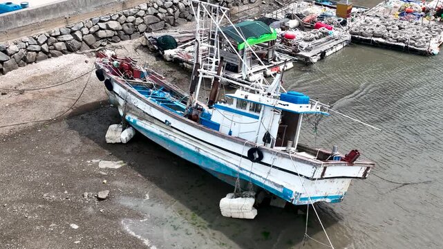 Static aerial drone view of fishing boat resting in a tidal harbor at low tide in South Korea