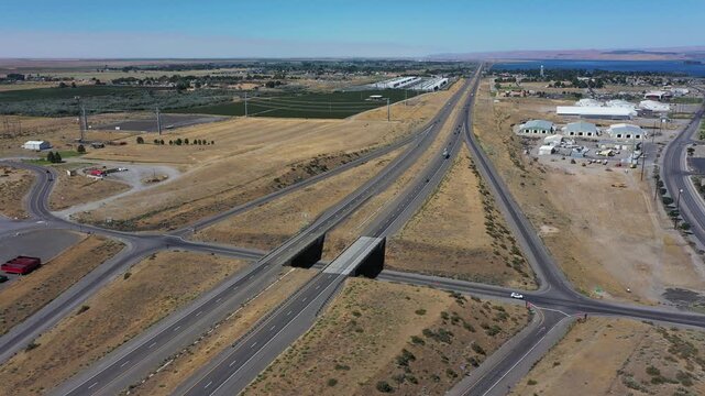 4K aerial drone footage of Interstate I-84 freeway near Boardman, Oregon, USA on a hot summer day. Static aerial view of low traffic, highway overpass, intersections, entrance ramps and dry landscape