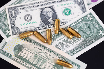Fototapeta premium Ammunition cartridges scattered on US dollar banknotes. Concept of financial crime, illegal money, organized crime, weapon financing, violence, corruption and security threats.
