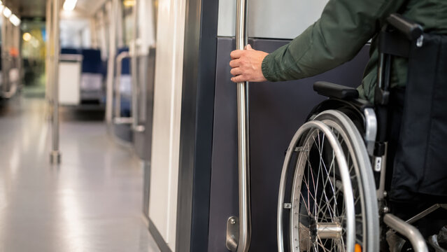 Wheelchair user engaging in activity on public transportation, holding rail for support, independence and accessibility emphasized
