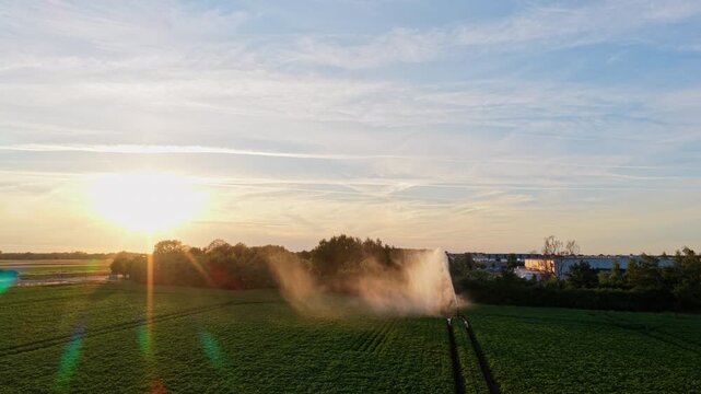 Sprinkler irrigation system watering field. Wind mill for renewable electric energy production. Irrigation system and windmill in rural area. Agriculture irrigation. Cultivation and harvest