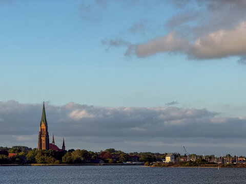 Schleswig Cathedral steeple across water at sunset in Germany