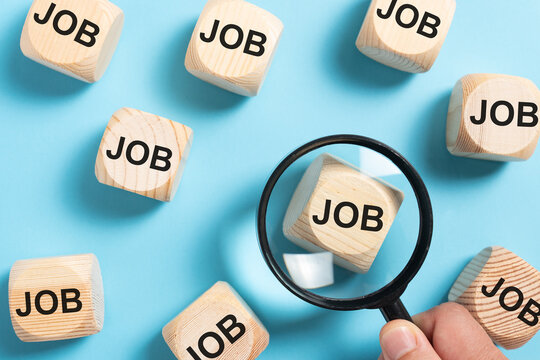 Wooden blocks labeled job arranged on a blue background with a magnifying glass representing employment, recruitment, career searches, hiring, and finding work.