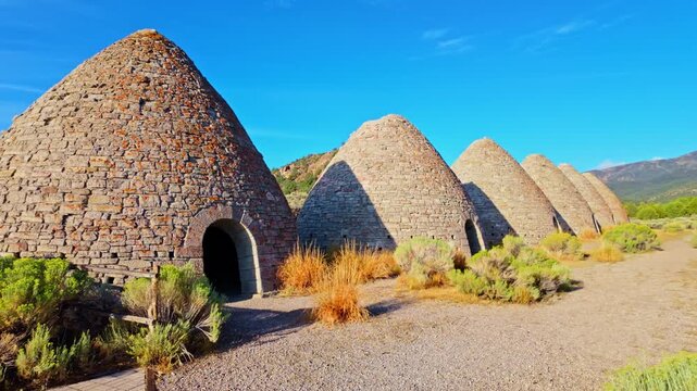 Row of beehive stone kilns standing under blue sky at Ward Charcoal Ovens State Historic Park in Nevada