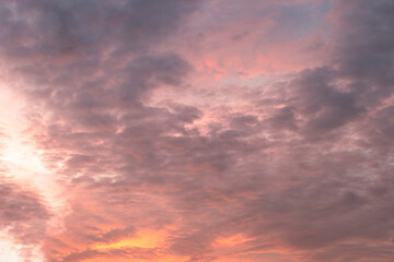 Fototapeta premium At sunrise or sunset, clouds—streaked with various hues like orange and reddish-yellow—lend a dramatic quality to the sky.
