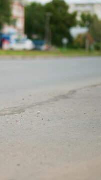 Vehicle travels steadily along street in city setting. Blue car remains stationary among background elements. Asphalt surface appears clean except for minor imperfections