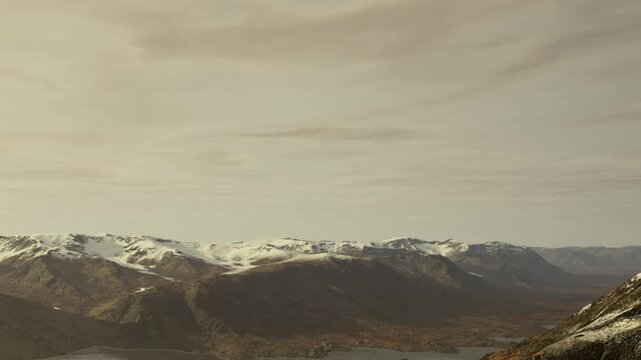 Snow covers the peaks of mountains in a remote area. Clouds are present in the sky above. The landscape shows rocky terrain and hints of lower elevations with less snow.