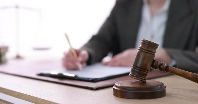 Professional lawyer working at wooden table in office, focus on gavel