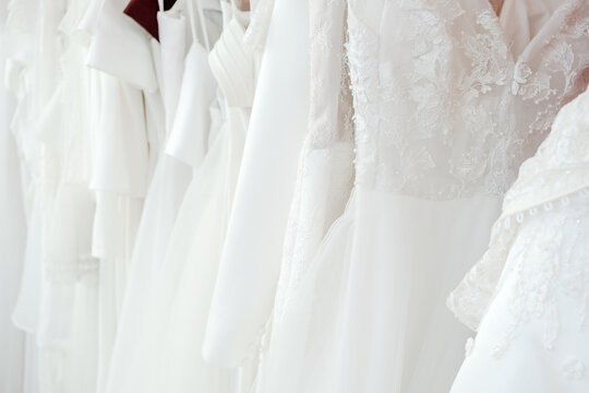 wedding dress, bridal gown, lace, white, boutique, marriage, fashion collection of elegant white silk and tulle dresses hanging on a rack in a luxury bridal shop for a bride.