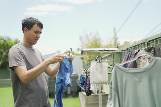 laundry, man, hanging, clothesline, domestic, chores, drying clothes in a backyard garden, authentic lifestyle photography of a middle-aged male performing daily household tasks.