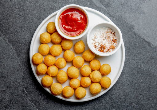 Fried potatoes ball, crocettes on white plate with tomato sauce, slate background, top view