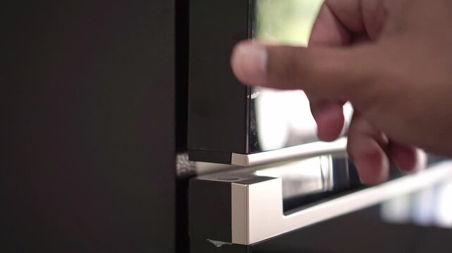 Person closing fridge door close up view, modern kitchen appliance, household routine and daily chore concept.