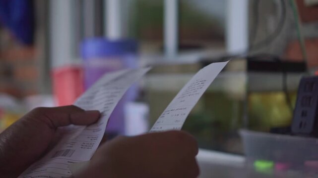 hand of person checking printed receipt, reviewing bill and QR code, financial transaction and shopping concept