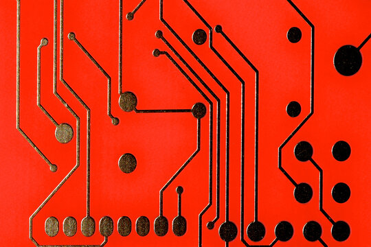 Closeup of red circuit board with conductor traces