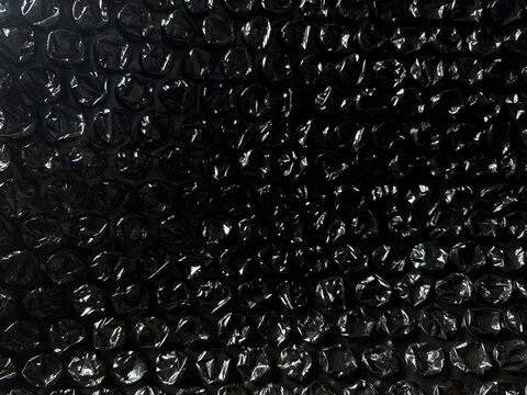 Black bubble wrap texture background for packaging and protection concept. shiny black plastic.