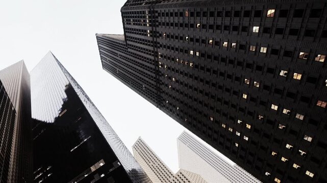 People walk along streets surrounded by tall buildings. Glass walls reflect light as clouds hover above. The scene shows an urban area filled with modern architecture and busy life.