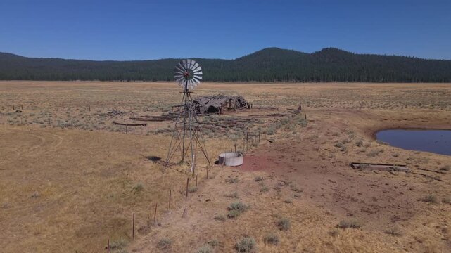 Drone flyby reveals windmill, cabin ruins, and wildlife watering pond on remote Lassen County rangeland, California.