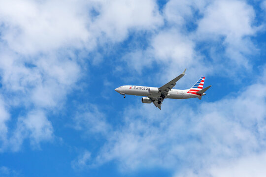 Tustin, CA, USA - August 7, 2026: A American Airlines airplane in flight with landing gears out against a blue cloudy sky coming in for a landing.