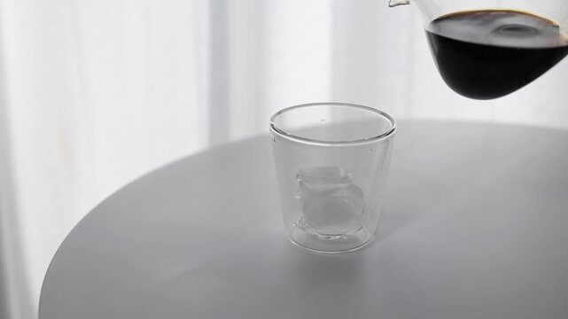 Pouring Iced Coffee into Clear Glass with Ice at Home Cafe