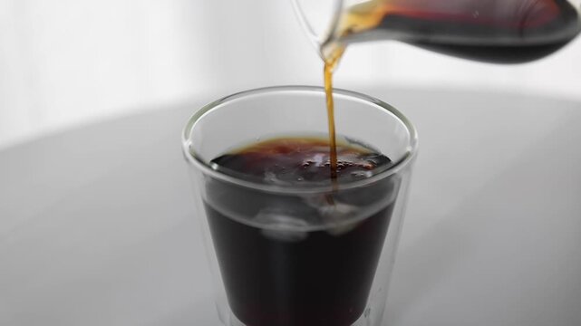 Pouring Iced Coffee into Clear Glass with Ice at Home Cafe