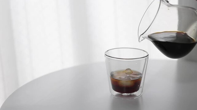 Pouring Iced Coffee into Clear Glass with Ice at Home Cafe