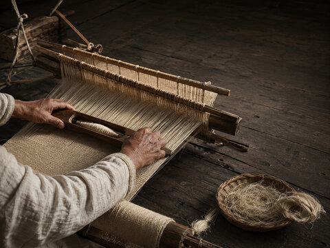 Close up of a traditional Korean hemp loom with warp threads shuttle and woven cloth in low side light