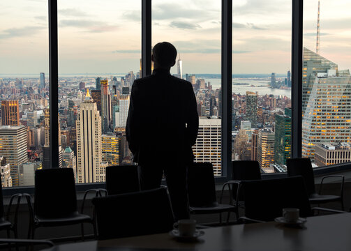 Back view of a businessman looking through window before meeting in New York City