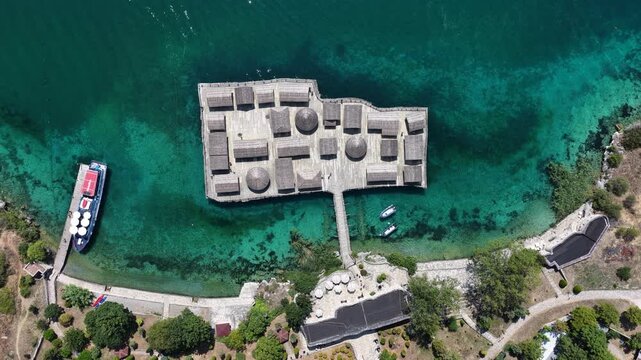 Aerial drone view of Bay of Bones on Lake Ohrid, North Macedonia, featuring the historic Fortress at the Bay of Bones surrounded by crystal clear turquoise lake water and mountains
