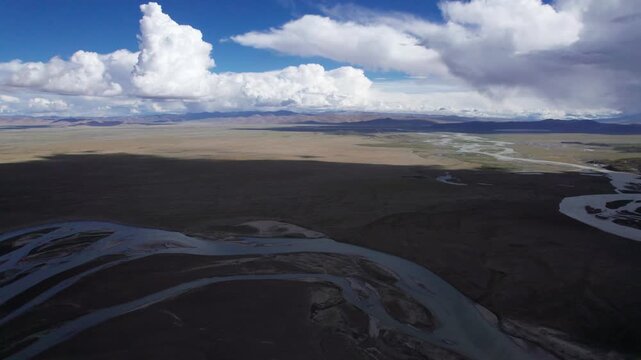 Drone view landscape along Chinese National highway G219, mountains and wetland river with blue sky and white clouds background in sunny day in Tibet, China, 4k real time footage b roll travel concept