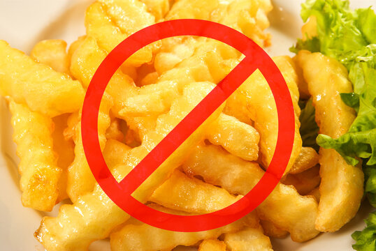 Red circle with a line through it over delicious crinkle-cut fries, indicating a prohibition of French fries