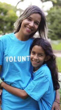 Volunteer mother and daughter hugging and celebrating outdoors - Charity team and community support concept - Vertical video
