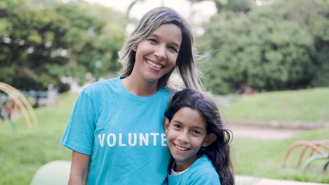 Volunteer mother and daughter hugging and celebrating outdoors - Charity team and community support concept