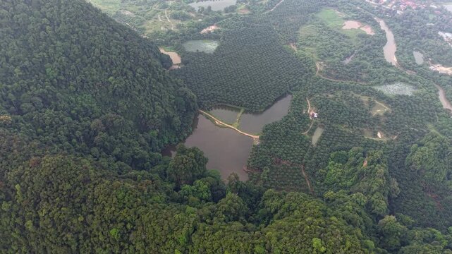 High-altitude drone view captures forested valley and central lake at Kampar, Perak