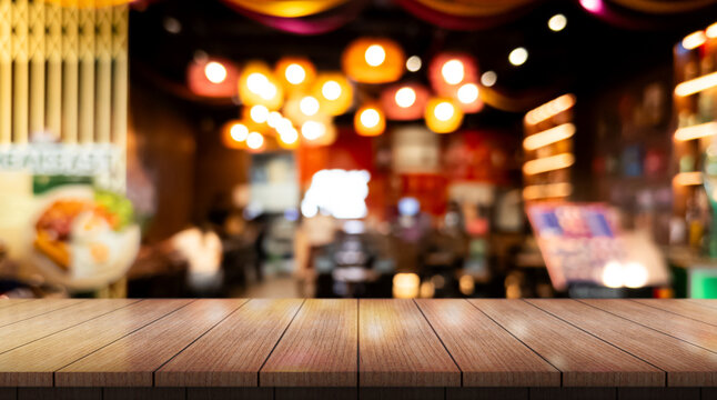 Empty wooden table top with lights bokeh on blur restaurant background.