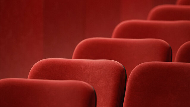 Rows of empty red velvet cinema chairs arranged in a neat line inside dark movie theater