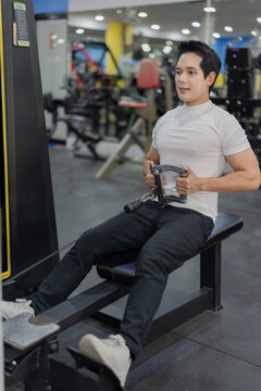 Asian man performing seated cable row exercise on machine in gym