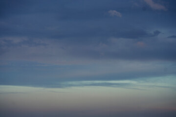 Obraz premium A serene and peaceful view of soft dark clouds floating gently across a wide open blue sky, creating a calming and tranquil atmospheric natural backdrop. 