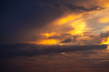 Obraz premium A stunning and dramatic sunset sky filled with vibrant orange and golden clouds, creating a peaceful and inspiring natural atmospheric background. 