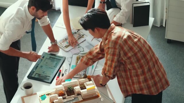 Smart architect or civil engineer writing building structure idea on note and stick on blueprint. Aerial view of manager working together with diverse colleague and show house plan. Alimentation.